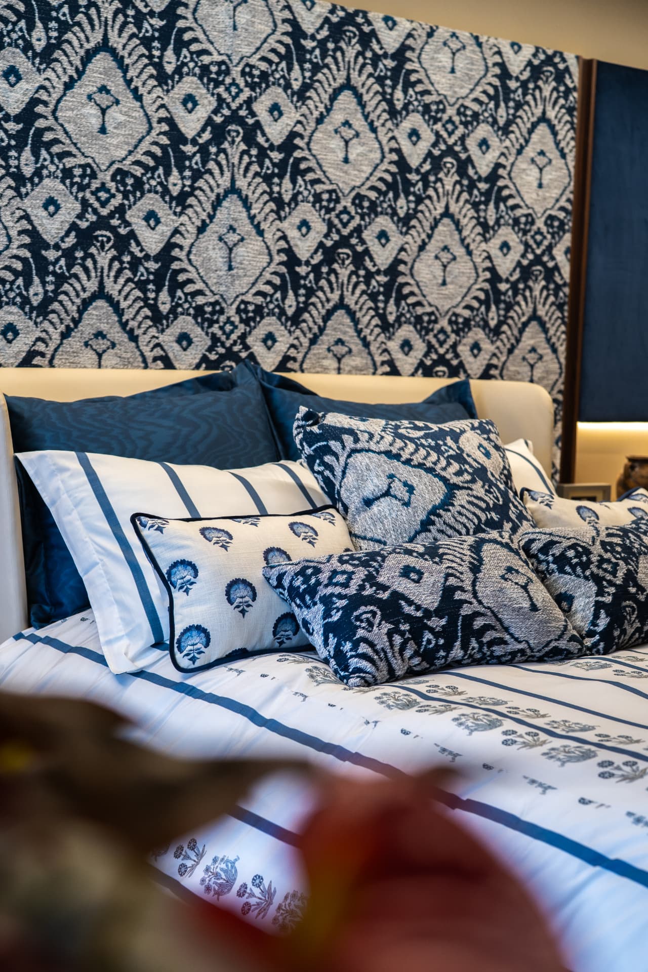Detalhe da cama Comporta com almofadas de jacquard azul e fronhas listradas