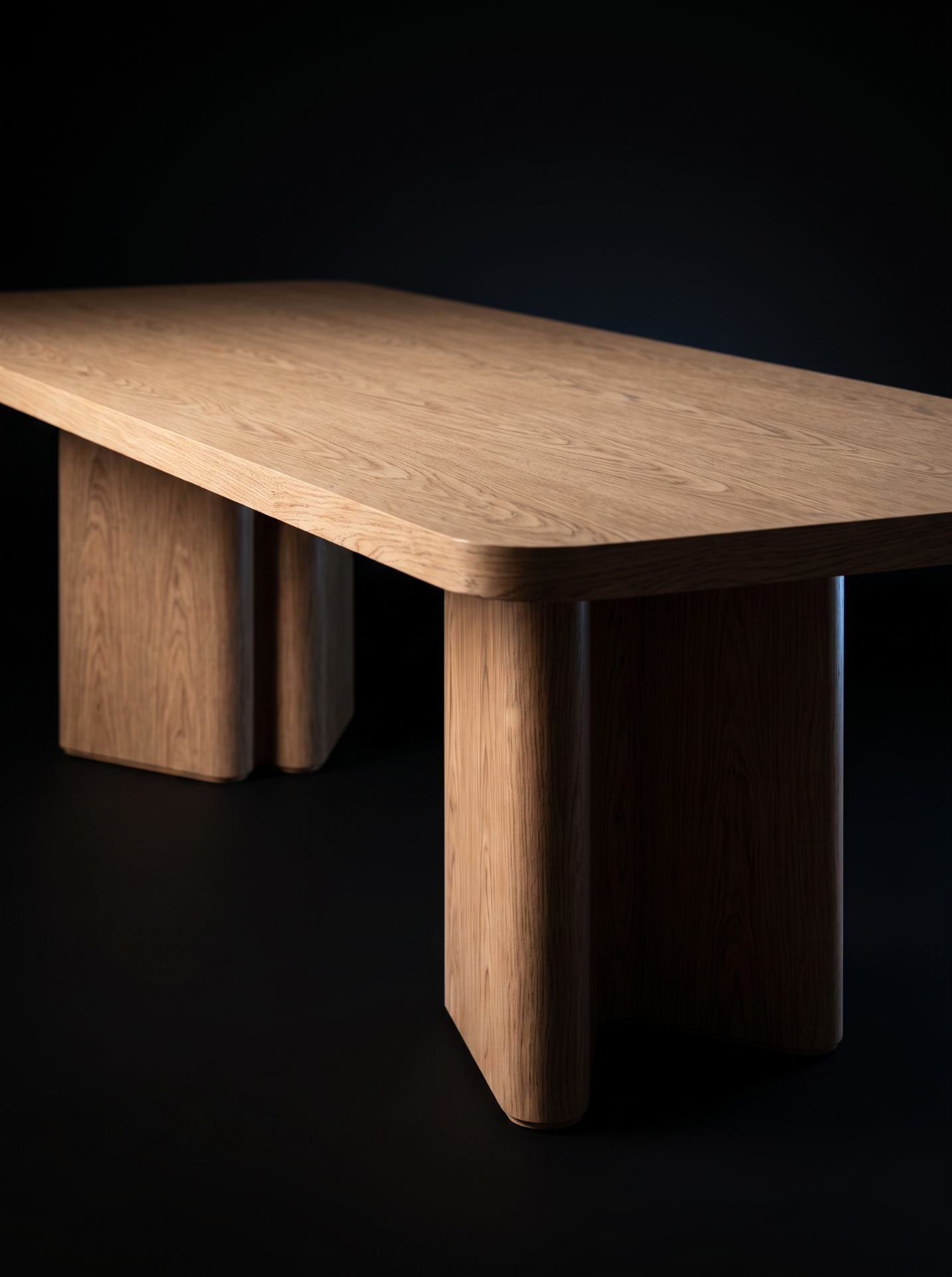 Detalhe da Mesa de Jantar Pejab, evidenciando os veios da madeira do tampo e o desenho robusto das bases, sobre fundo escuro