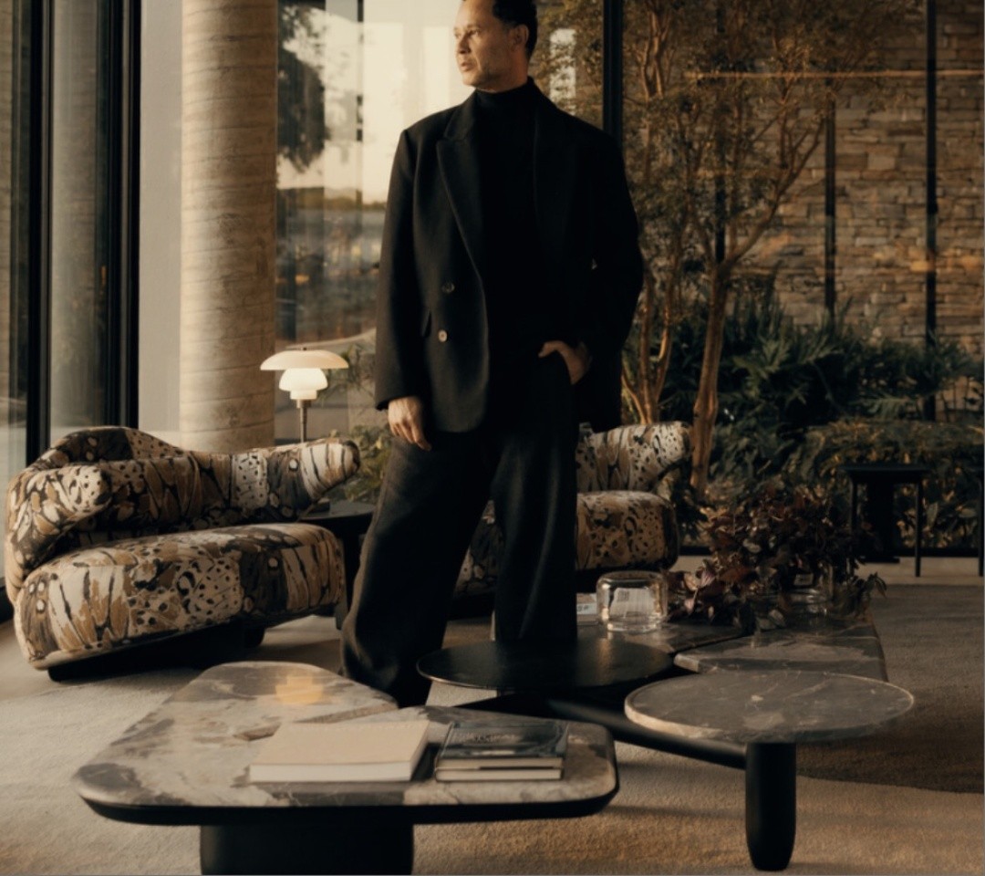 Retrato de Maurício Bomfim, arquiteto e designer, em ambiente contemporâneo com poltronas Elefante e mesas de mármore