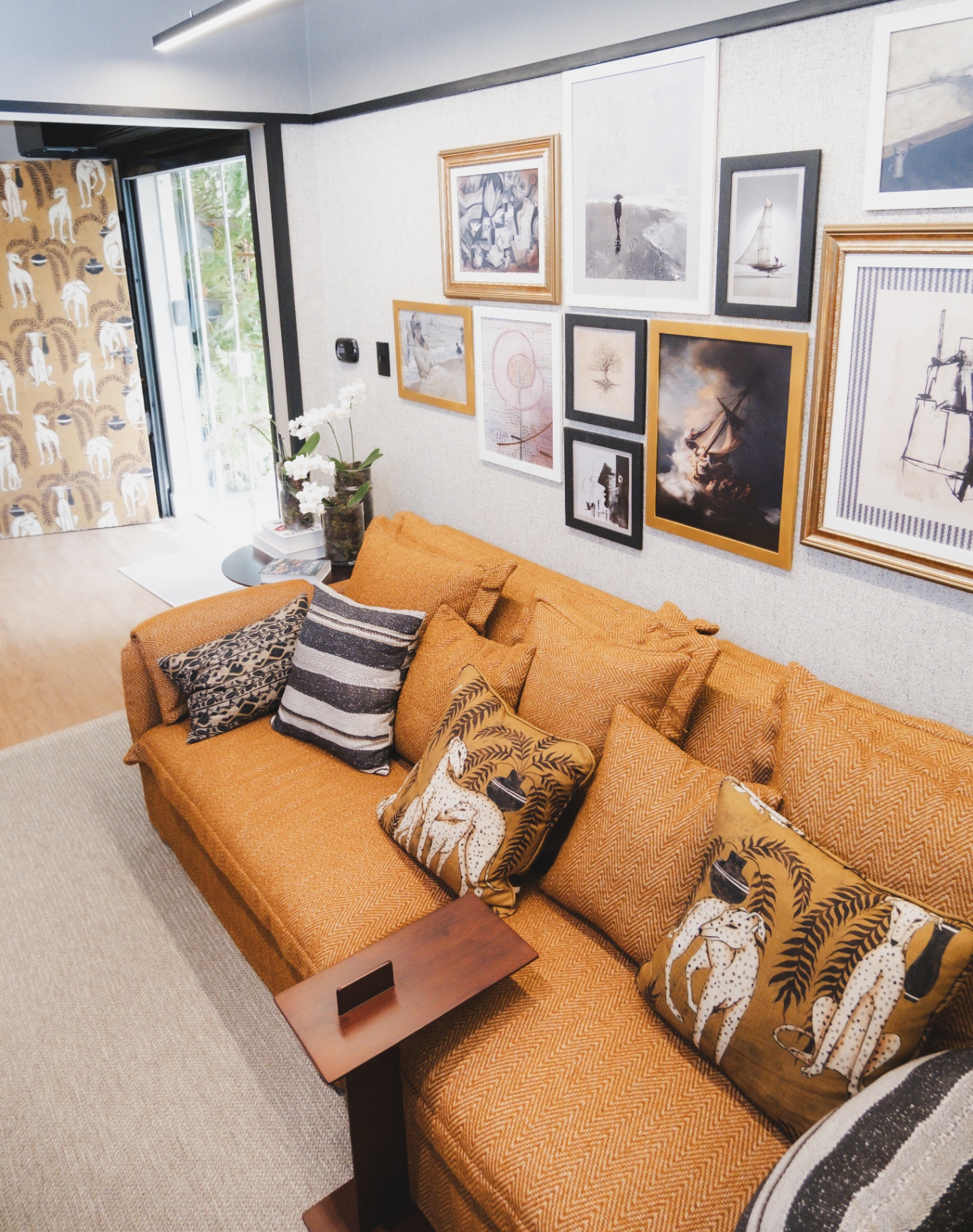 Sala de estar Cosmopolitan com sofá terracota, parede-galeria de quadros e papel de parede de galgos