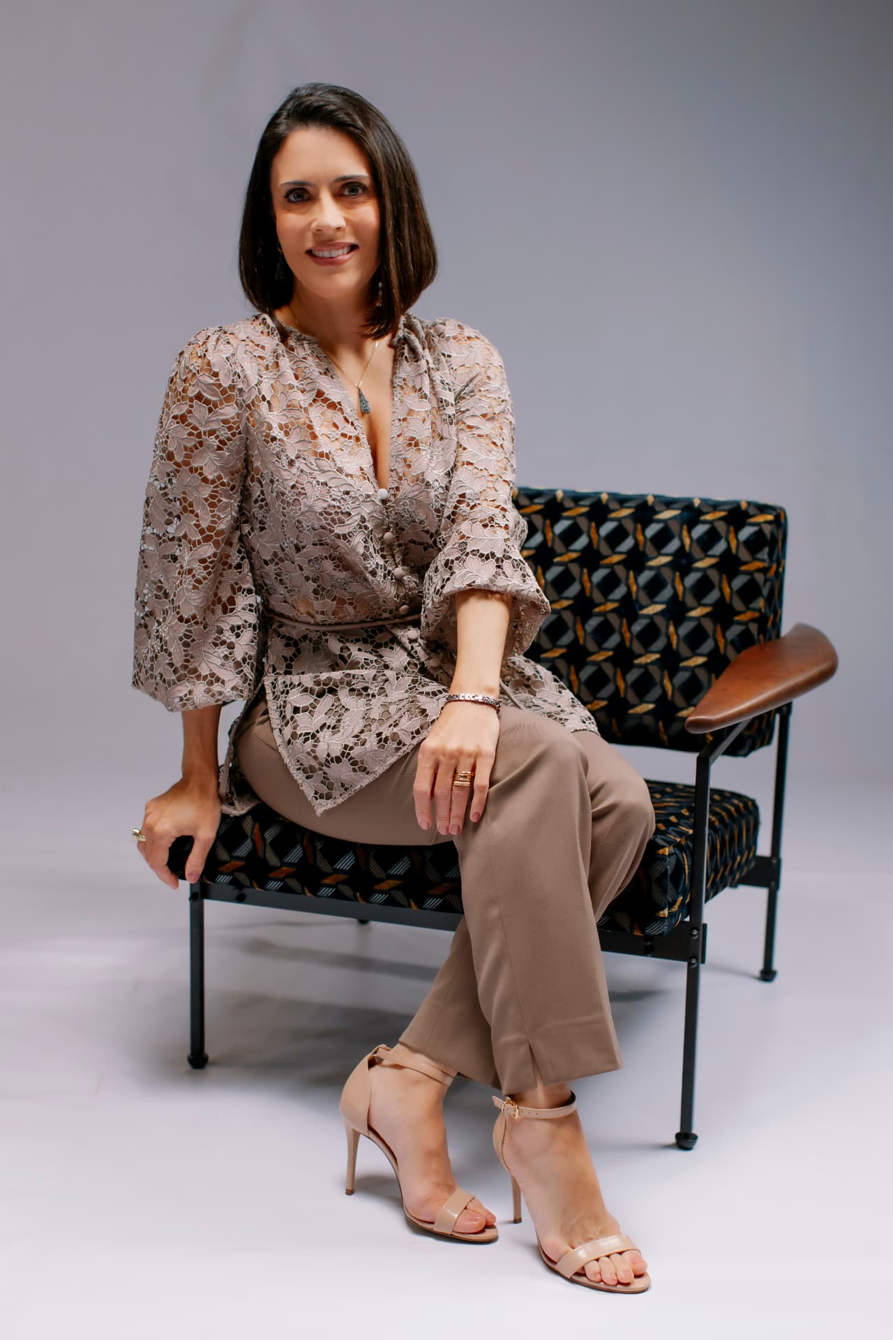 Retrato de participante sentada em poltrona de estrutura metálica