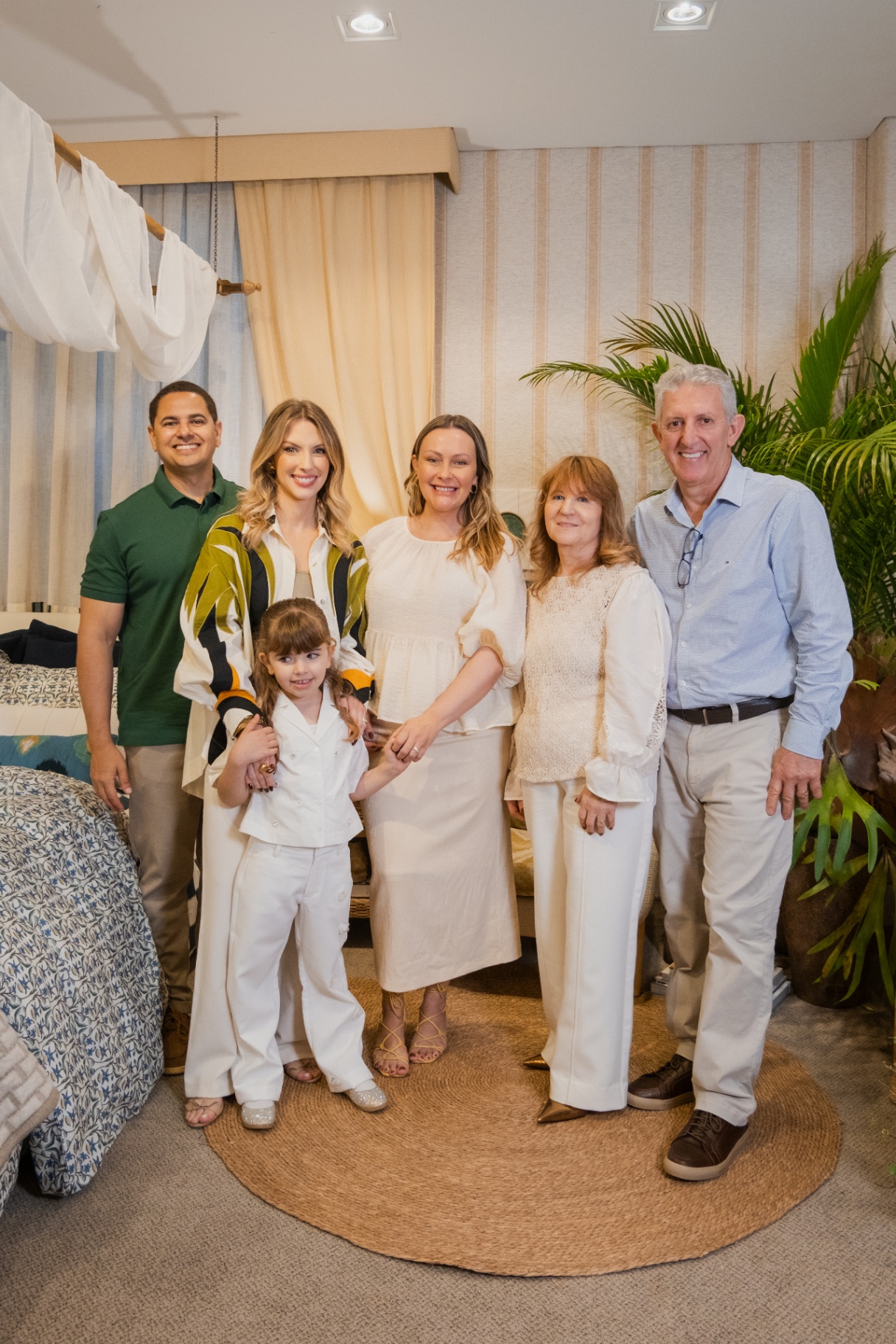 Família Luize Home reunida no ambiente Zanzibar, entre cortinas listradas e cama com roupa de cama estampada