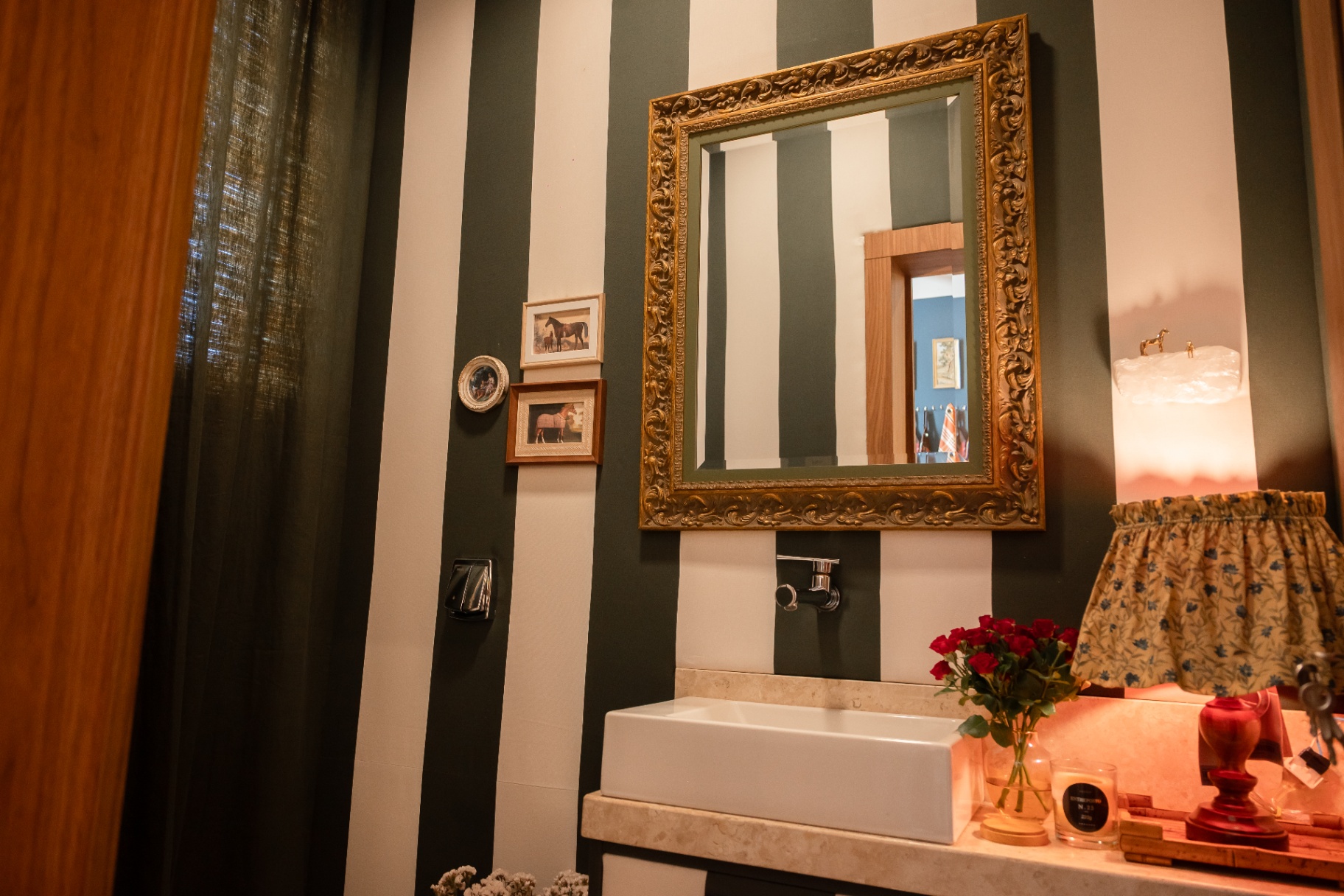 Lavabo em listras verde e branco com espelho de moldura dourada e vela Entreposto