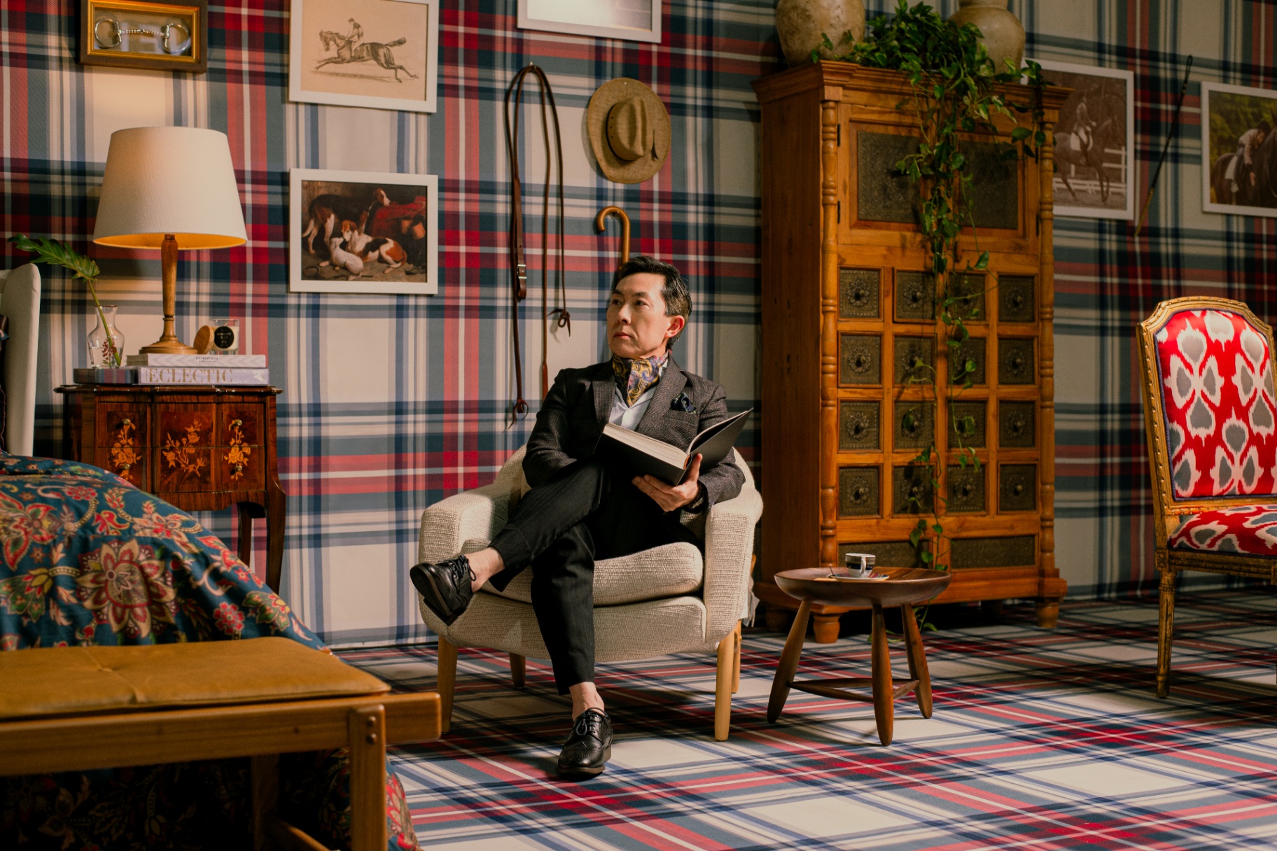 Leitura em poltrona no ambiente tartan, com xadrez em parede, tapete e estofados