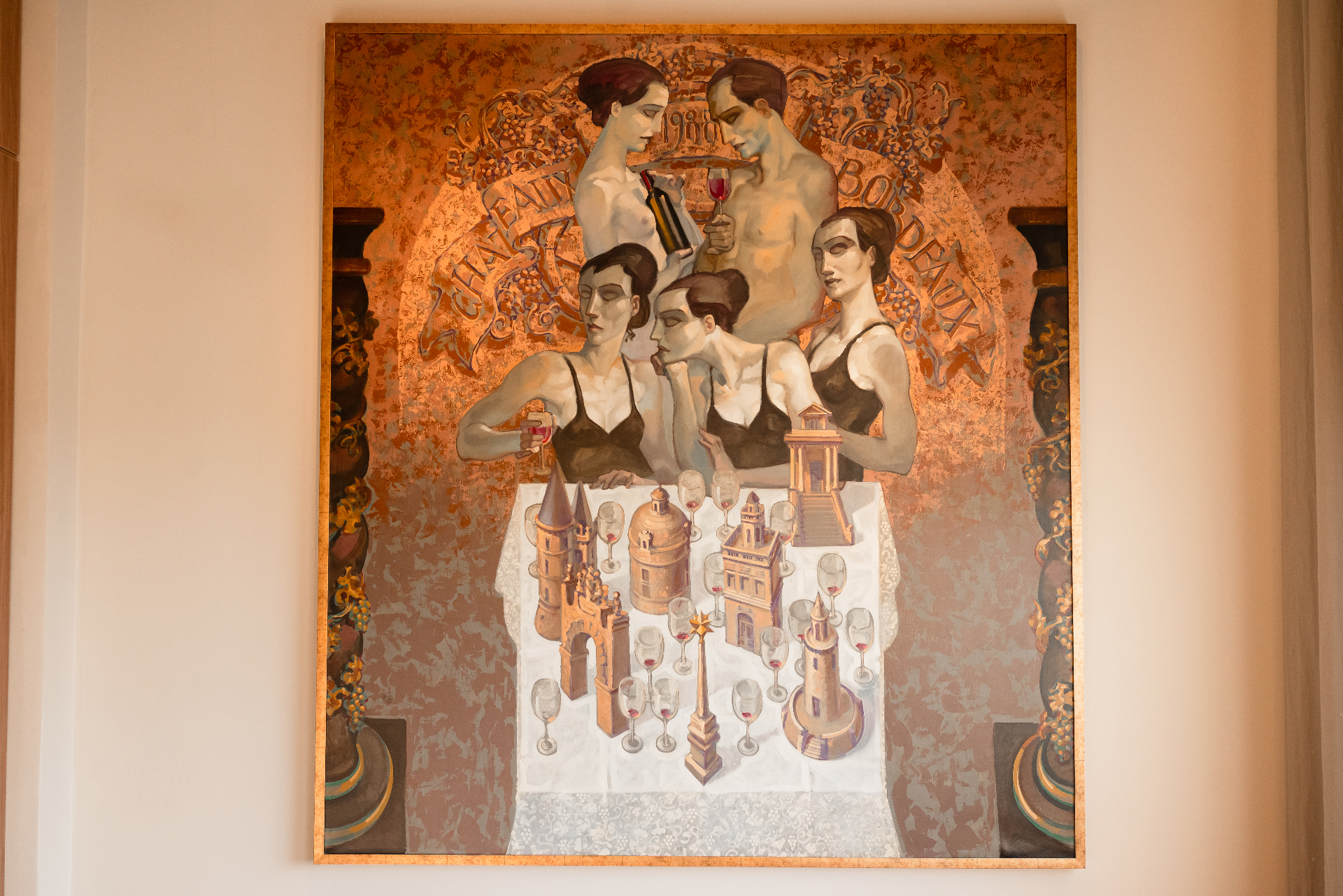 Chateaux Bordeaux, Juarez Machado, 1988, óleo sobre tela em grande formato retratando figuras alegóricas em torno de uma mesa com miniaturas de castelos e taças de vinho, moldura em folha de ouro