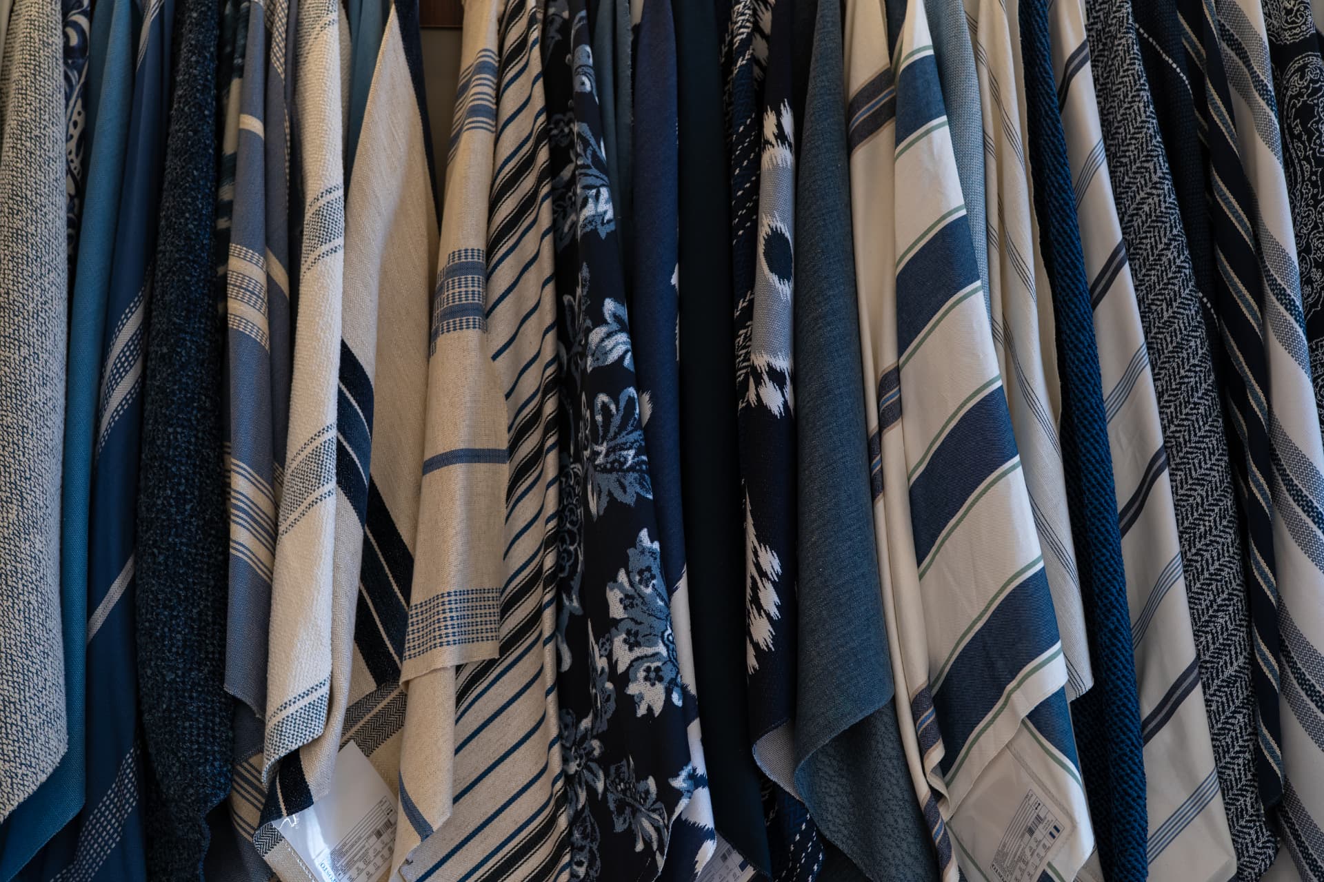 Tecidos em tons de azul, listras e jacquard pendurados lado a lado