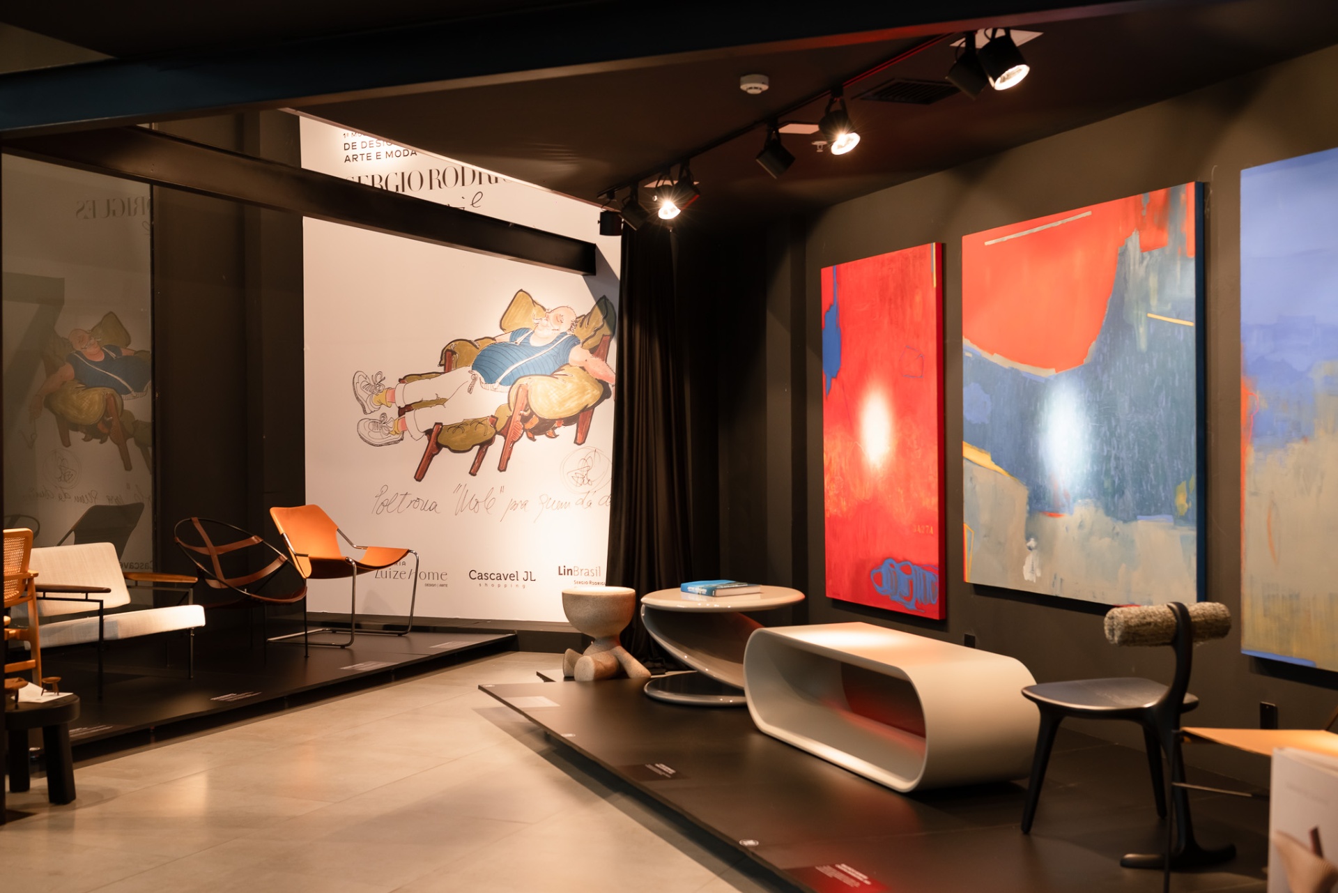 Vista da 1ª Mostra de Design na Galeria Luize Home, com poltronas assinadas e obras contemporâneas