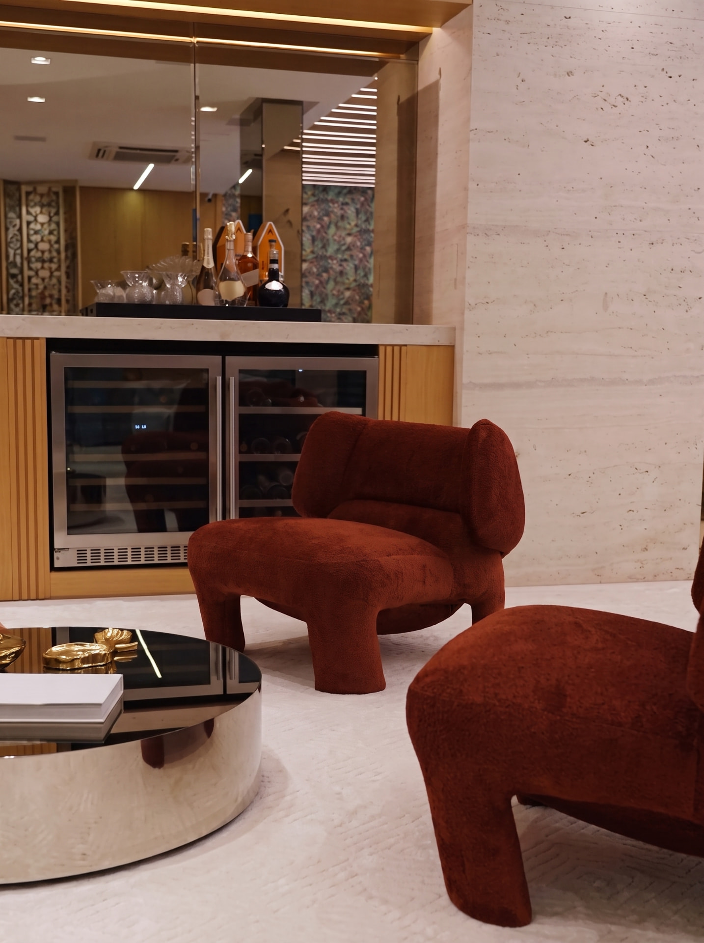 Ambiente de estar com poltronas terracota e mesa espelhada · Casa de Michele Zanini